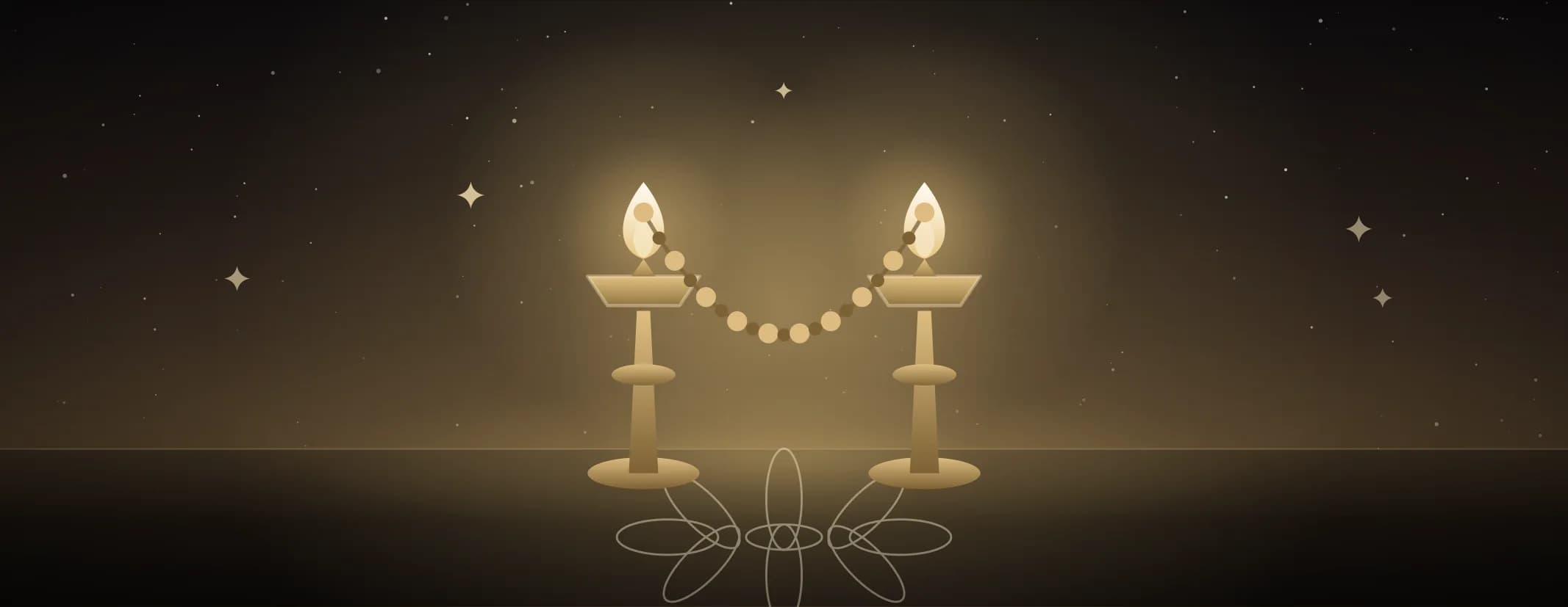 Two lamps placed close together and burning, a short beaded garland between them, on a floor marked with a kolam.